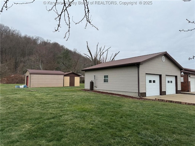 rear view of property with a lawn, a garage, and a storage shed