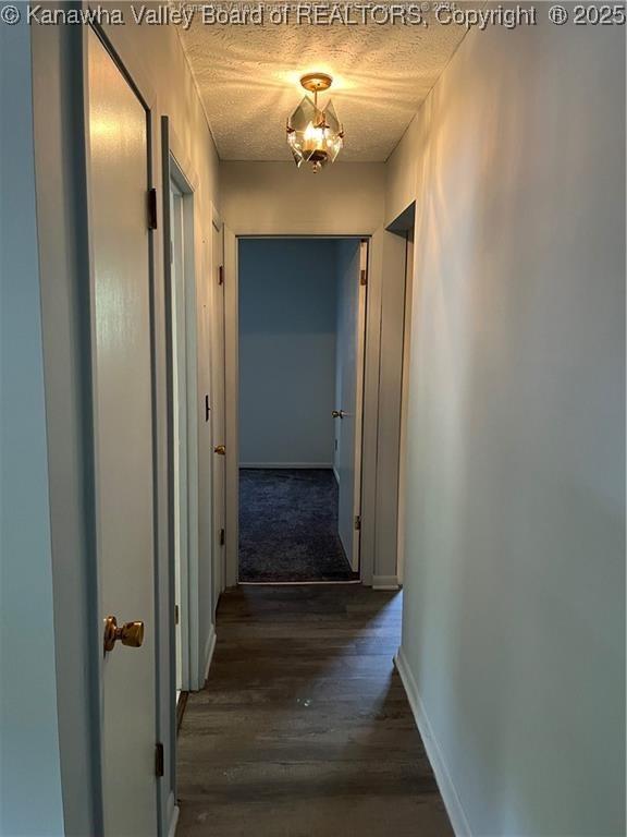 hallway with dark hardwood / wood-style floors and a textured ceiling