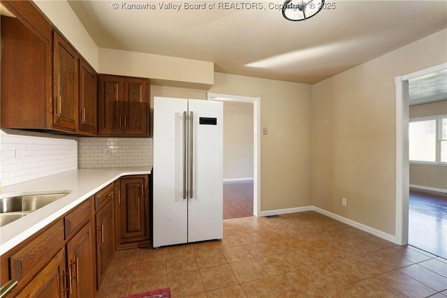 kitchen featuring sink, high end white refrigerator, backsplash, and light tile patterned floors