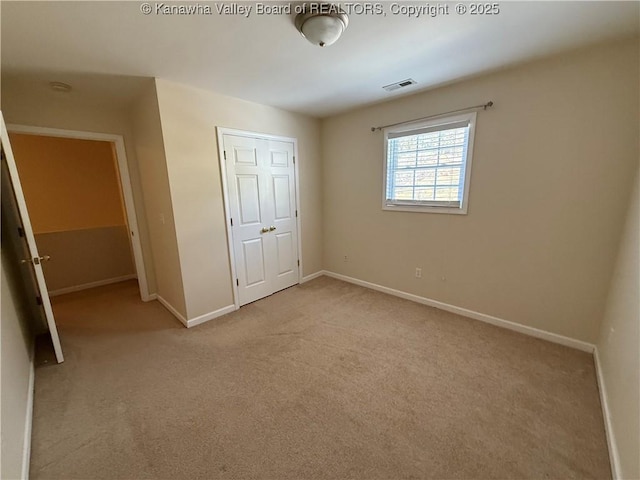 unfurnished bedroom with a closet and light colored carpet