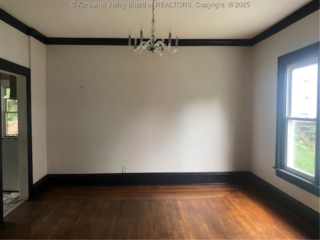 unfurnished room featuring hardwood / wood-style floors, crown molding, and an inviting chandelier