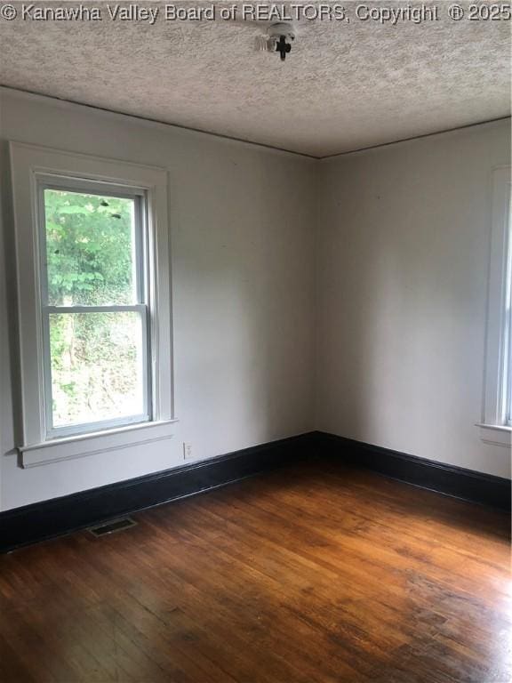 empty room featuring dark hardwood / wood-style flooring and a textured ceiling