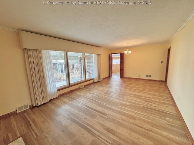 unfurnished room featuring a textured ceiling, crown molding, an inviting chandelier, and light hardwood / wood-style flooring