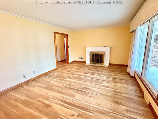 unfurnished living room featuring light wood-type flooring, a high end fireplace, and crown molding