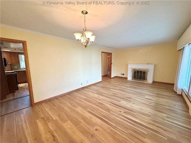 unfurnished living room with an inviting chandelier, crown molding, light hardwood / wood-style flooring, and a high end fireplace