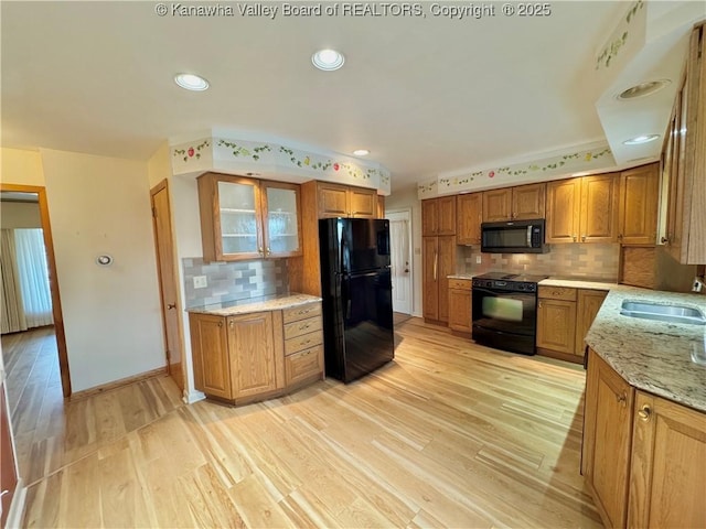 kitchen with light hardwood / wood-style flooring, sink, black appliances, and light stone countertops