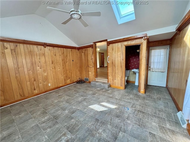 unfurnished bedroom featuring lofted ceiling with skylight and wooden walls