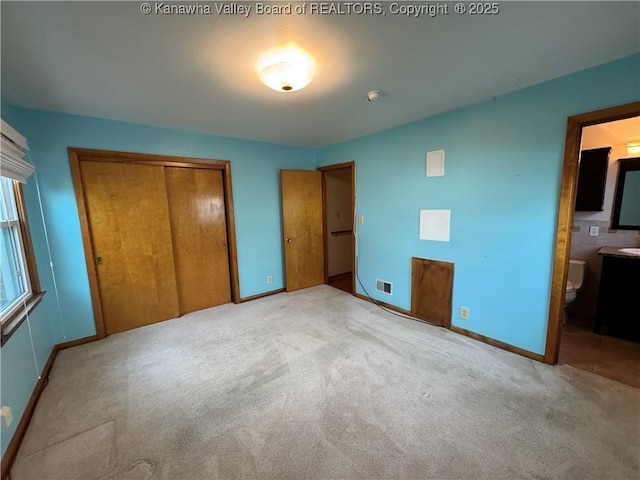 unfurnished bedroom with light colored carpet, ensuite bath, and a closet