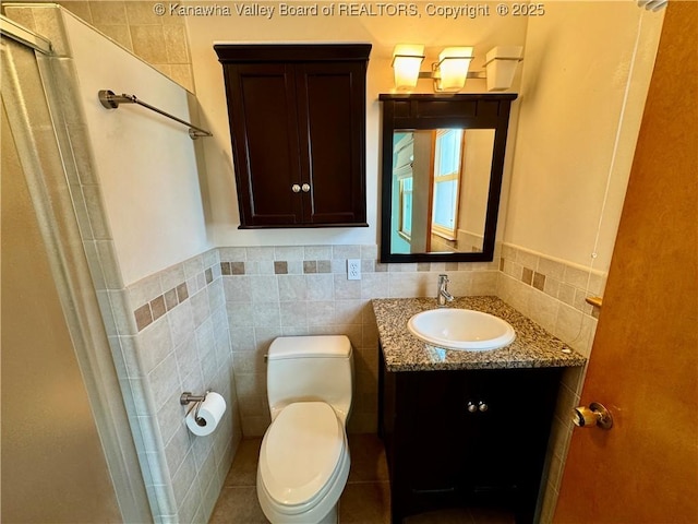 bathroom with vanity, tile walls, and toilet