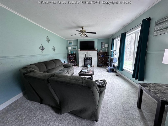 carpeted living room with ornamental molding, a ceiling fan, a brick fireplace, a textured ceiling, and baseboards