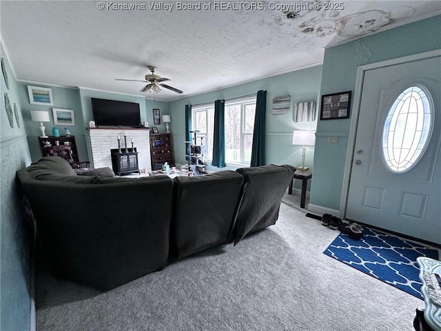 carpeted living area featuring a textured ceiling, ceiling fan, baseboards, and crown molding