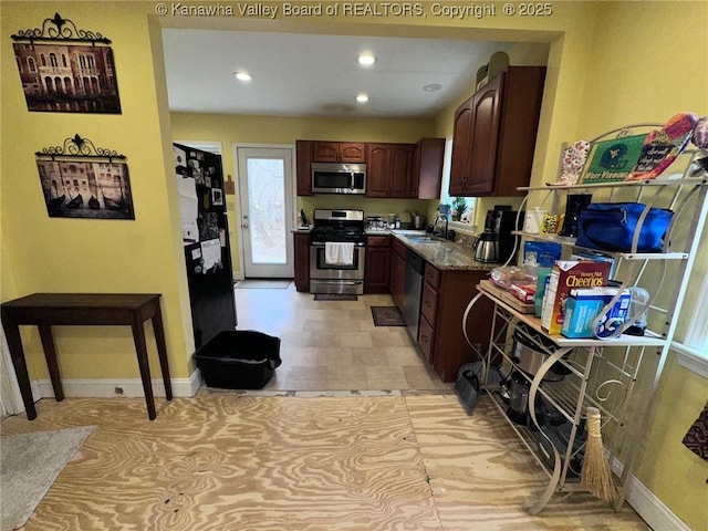 kitchen featuring recessed lighting, a sink, baseboards, appliances with stainless steel finishes, and dark stone countertops