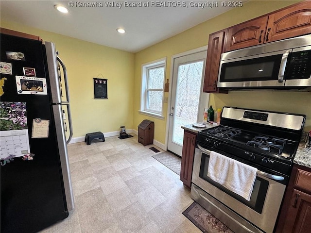 kitchen with baseboards, appliances with stainless steel finishes, light stone countertops, light floors, and recessed lighting