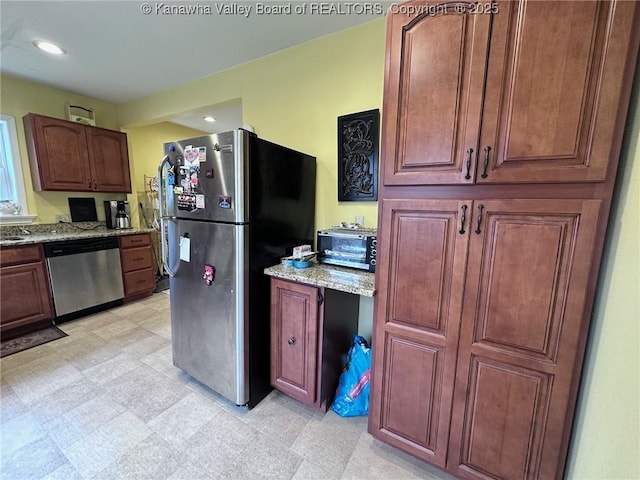 kitchen with a toaster, appliances with stainless steel finishes, light stone counters, light floors, and recessed lighting