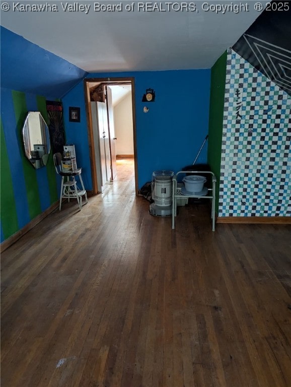 interior space with lofted ceiling, baseboards, and wood finished floors