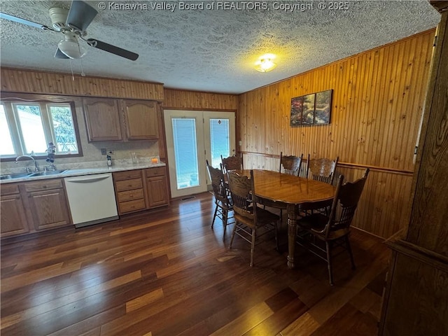 dining space featuring dark wood-style flooring, a textured ceiling, and wooden walls