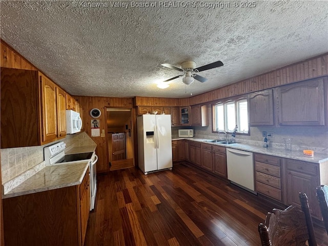 kitchen featuring a sink, dark wood finished floors, white appliances, brown cabinetry, and glass insert cabinets