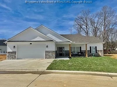 view of front of property with driveway, stone siding, an attached garage, and a front lawn