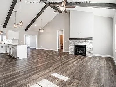 unfurnished living room featuring a fireplace, baseboards, dark wood finished floors, and beam ceiling