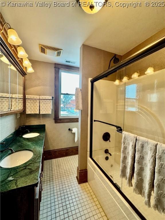 bathroom featuring double vanity, visible vents, combined bath / shower with glass door, and a sink