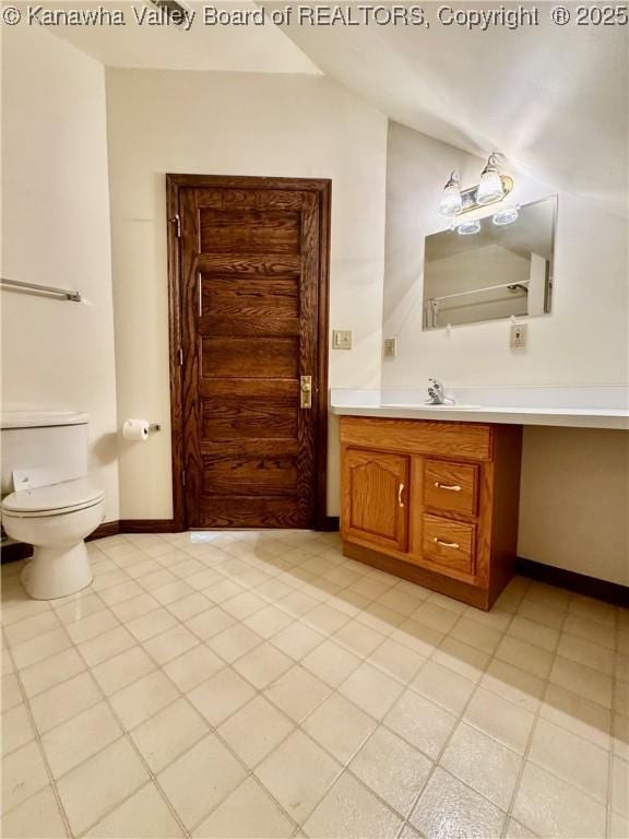 bathroom featuring lofted ceiling, baseboards, toilet, and vanity