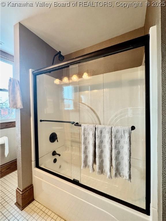 bathroom with shower / bath combination with glass door and tile patterned flooring