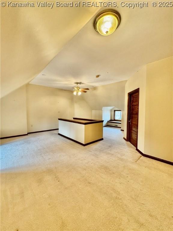 interior space with lofted ceiling, carpet, baseboards, and ceiling fan