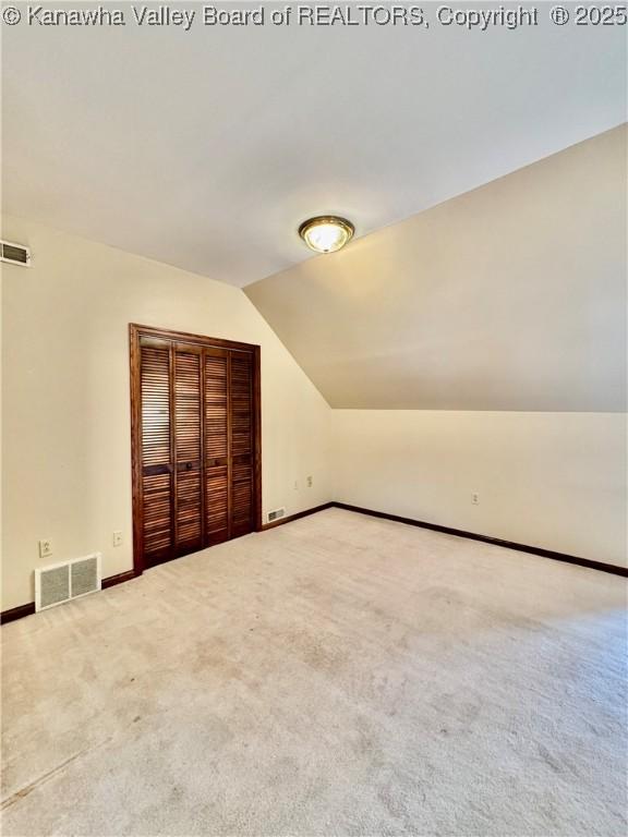 additional living space featuring lofted ceiling, carpet floors, visible vents, and baseboards