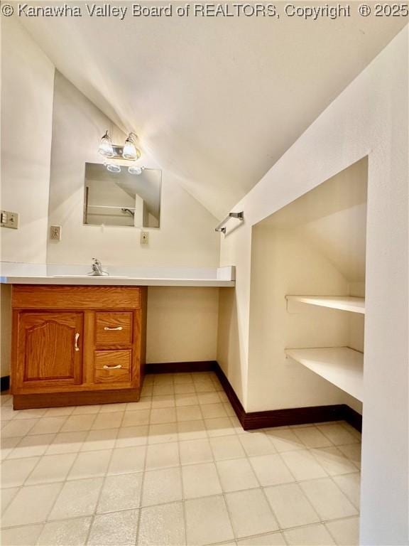 bathroom with baseboards, vaulted ceiling, and vanity