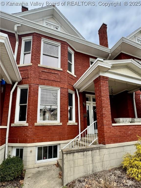 view of front of house featuring brick siding and a chimney