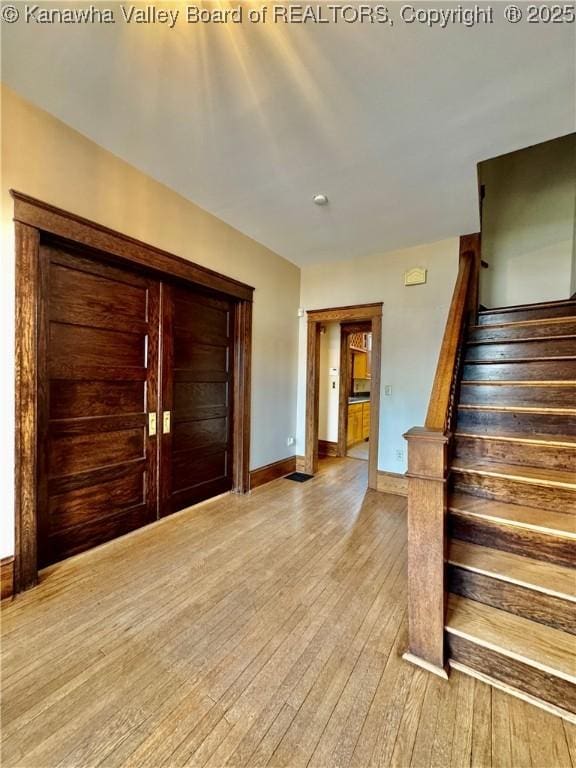 entryway with stairs, light wood-style flooring, and baseboards