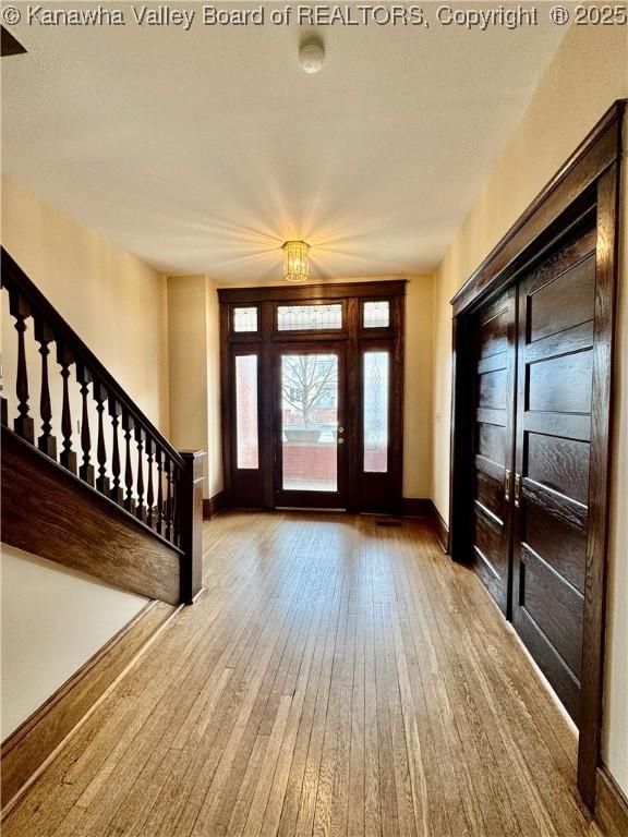 foyer with stairway, baseboards, and wood finished floors