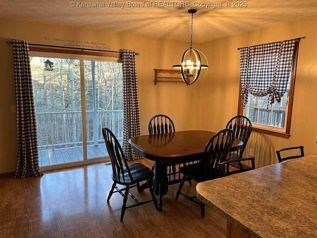 dining space with a notable chandelier, a textured ceiling, and wood finished floors