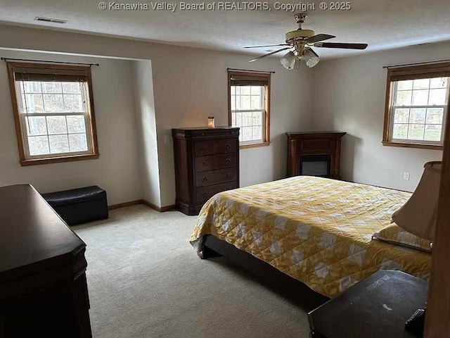 bedroom featuring light carpet, a ceiling fan, visible vents, and baseboards