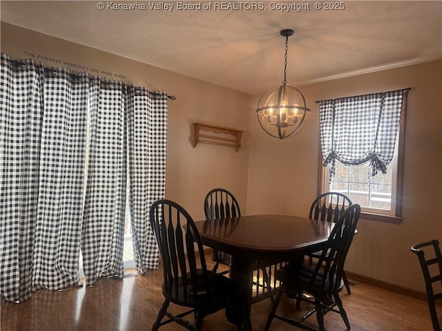 dining area with a chandelier, wood finished floors, and baseboards