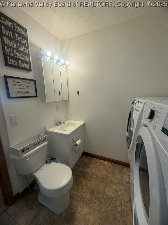 bathroom featuring a textured ceiling, toilet, vanity, baseboards, and washer and clothes dryer