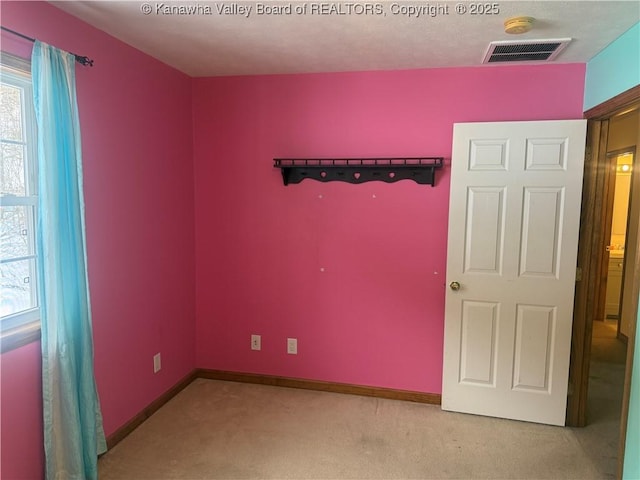 unfurnished room featuring baseboards, visible vents, and light colored carpet