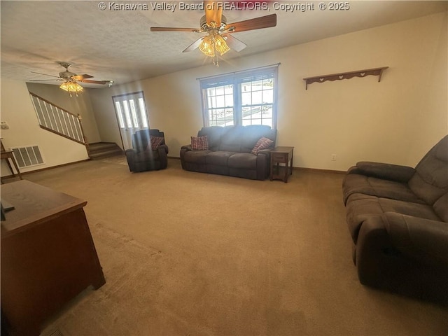 living area with carpet floors, visible vents, ceiling fan, a textured ceiling, and stairs