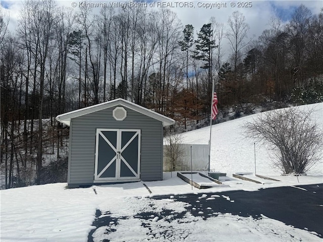 snow covered structure featuring a shed and an outdoor structure