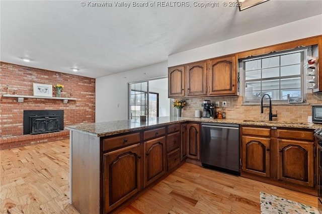 kitchen featuring a peninsula, light stone countertops, and stainless steel dishwasher