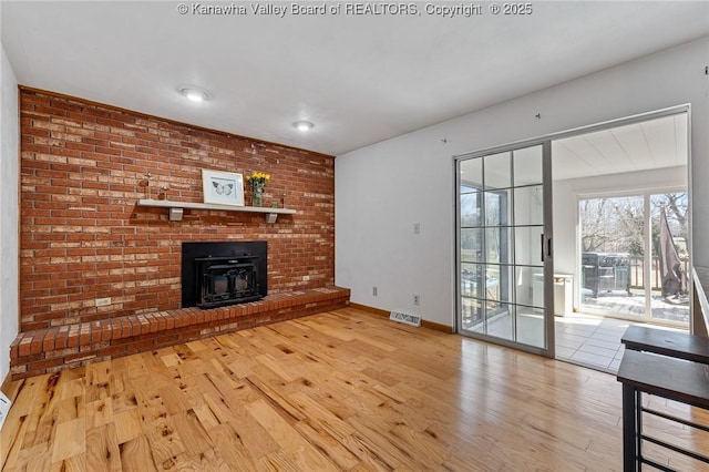 unfurnished living room with light wood-type flooring, baseboards, and visible vents