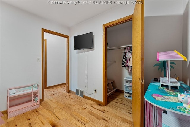 bedroom with light wood finished floors, baseboards, visible vents, a spacious closet, and a closet