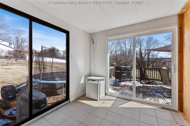 doorway featuring a wealth of natural light, baseboards, and light tile patterned floors