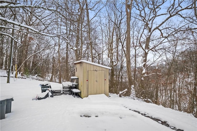 yard layered in snow with a storage shed and an outbuilding