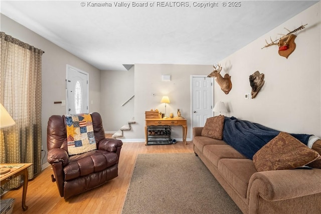 living area with light wood-style flooring, stairway, and baseboards