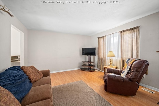 living area featuring wood finished floors, visible vents, and baseboards