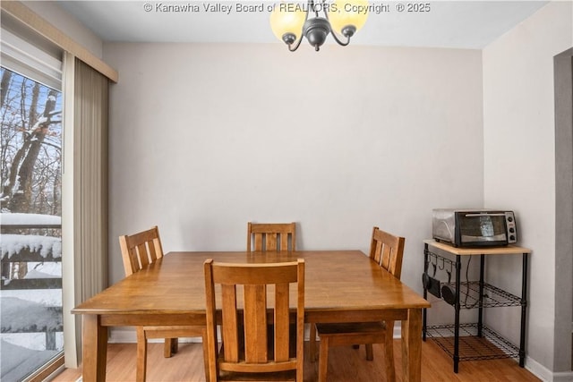 dining space featuring light wood finished floors, a toaster, and a notable chandelier