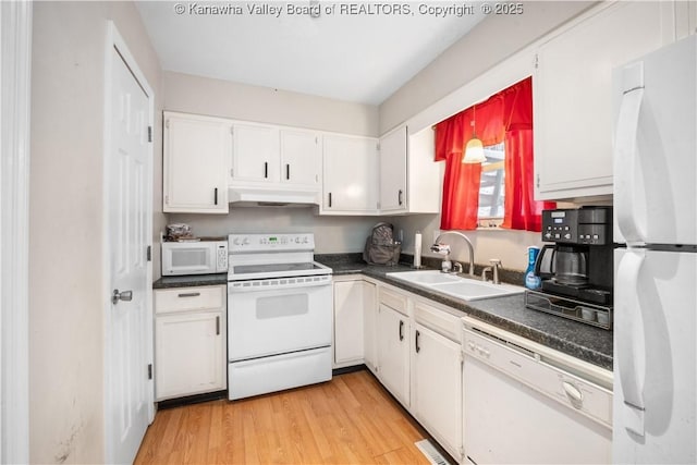 kitchen featuring dark countertops, white appliances, white cabinetry, and a sink