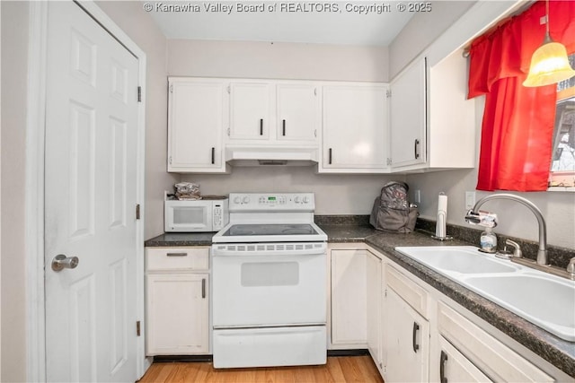 kitchen featuring white appliances, white cabinets, light wood-style floors, under cabinet range hood, and a sink