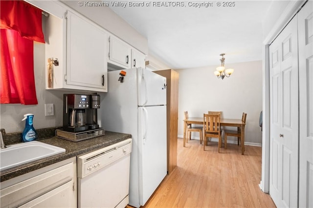 kitchen featuring light wood-style flooring, white appliances, a sink, white cabinetry, and dark countertops